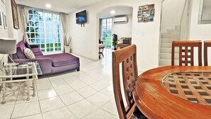 A living room with a purple sofa, a glass coffee table, and a wooden dining table. - Cozybeautiful house near to the beach (Acapulco de Juárez)