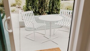 A patio area with a round table and two white chairs with striped backs. - Rose House (Seattle)