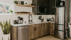 A modern kitchen with wooden cabinets, stainless steel appliances, and a built-in dishwasher. - Rose House (Seattle)