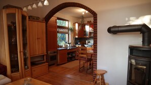 Una cocina acogedora con armarios de madera, una zona de comedor con mesa y una estufa de leña empotrada.