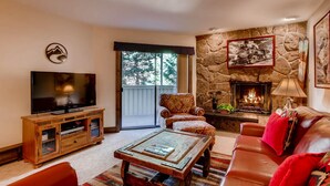 A cozy living room with a stone fireplace, a flat-screen TV, and comfortable seating. - Westwind 108 2BD 2BA Platinum Condo in Lionshead Village (Vail)