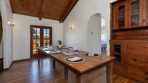 A dining area with a long wooden table set for four, wooden cabinets, and a vaulted ceiling. - Completely Renovated Old Time Los Alamos Home-- with recreation Barn! (Los Alamos)