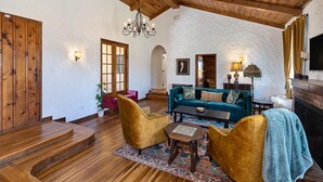 A spacious living room with a wooden staircase, a teal sofa, and a chandelier. - Completely Renovated Old Time Los Alamos Home-- with recreation Barn! (Los Alamos)