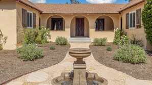 A courtyard with a central fountain, surrounded by arches and plants. - Completely Renovated Old Time Los Alamos Home-- with recreation Barn! (Los Alamos)