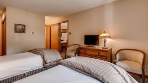 Habitación de hotel con dos camas, televisión, lámpara y una silla.