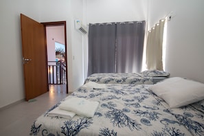 A bedroom with a bed, a window with curtains, and a door leading to a balcony. - Duplex no Solar Água Pipa por Carpediem (Tibau do Sul)