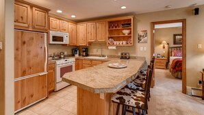 A kitchen with wooden cabinets, a granite countertop, and a breakfast bar with bar stools.