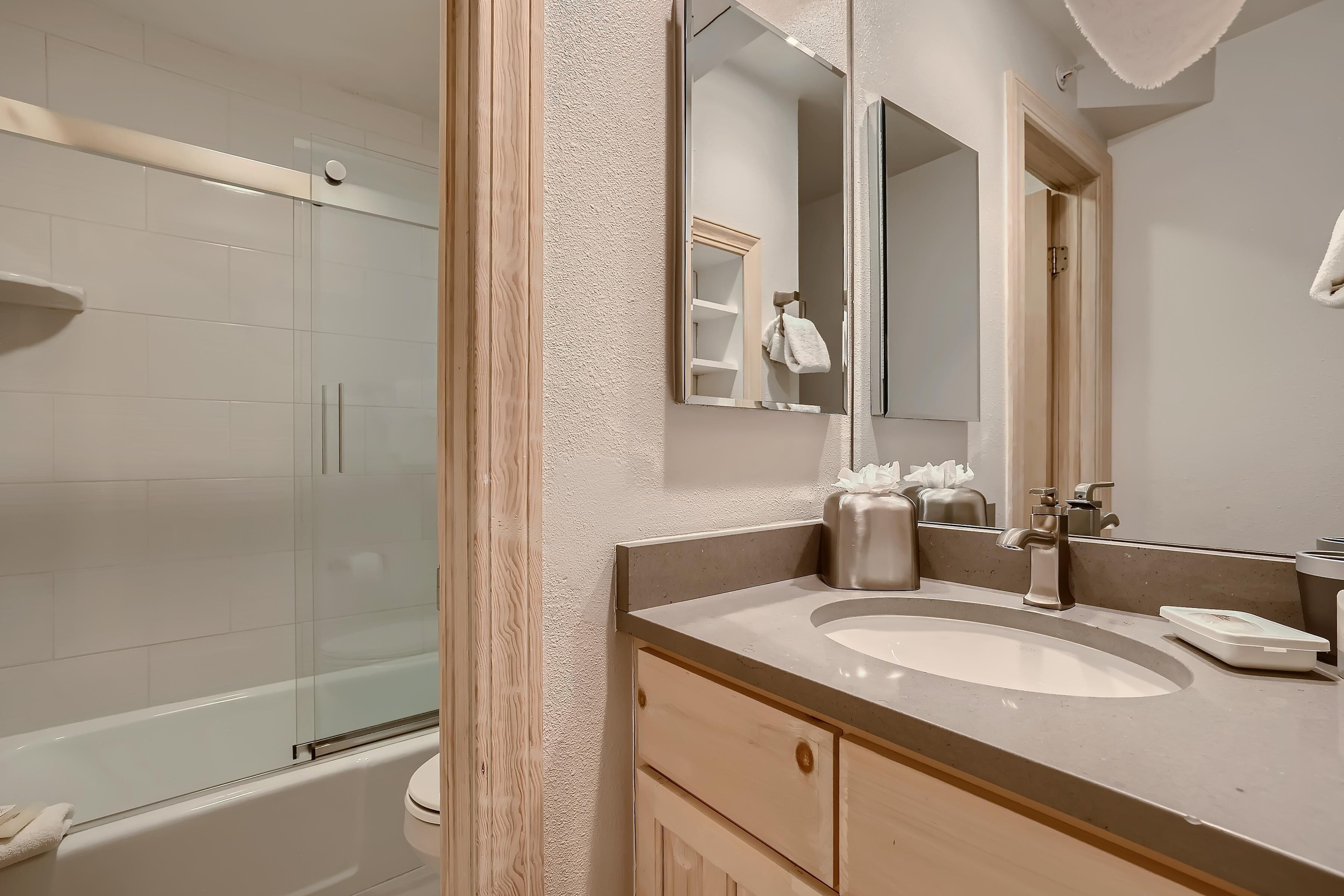 Un bagno con doccia vetrata, lavandino con specchio e porta asciugamani.