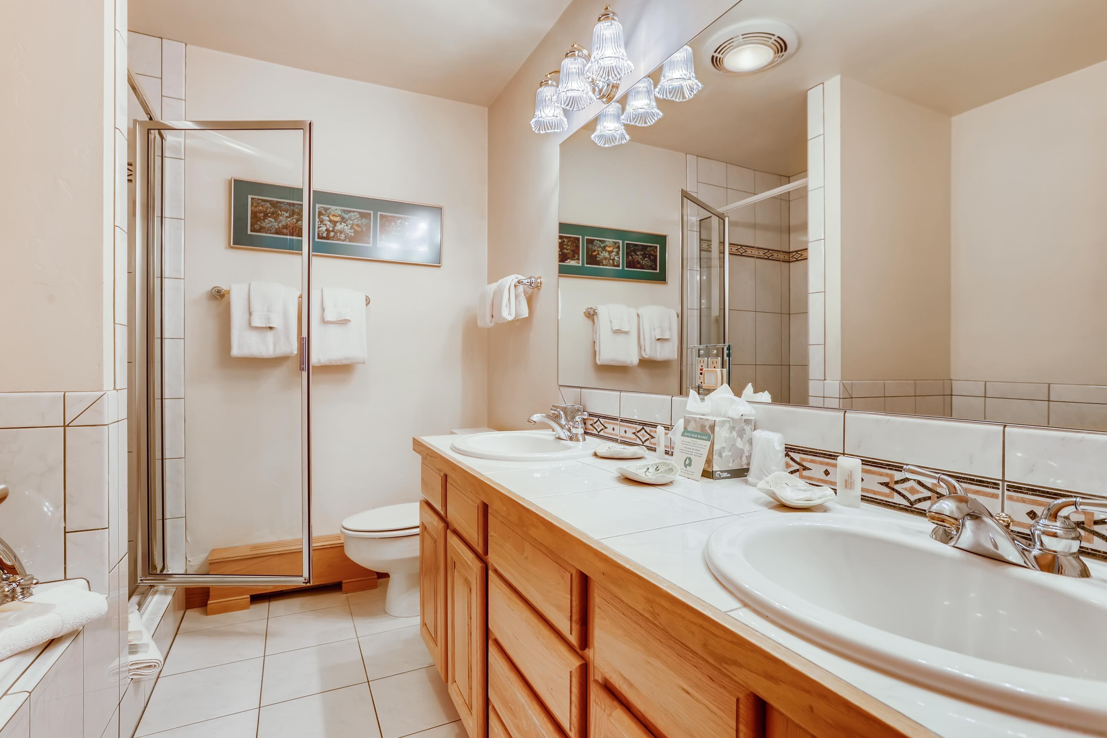 Un baño moderno con cabina de ducha de vidrio, un espejo grande y un mueble de tocador doble.