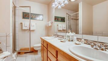Un baño moderno con cabina de ducha de vidrio, un espejo grande y un mueble de tocador doble.