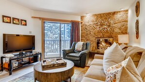 A modern living room with a flat-screen TV, leather sofa, and a stone accent wall. - Westwind 308 2BD Gold Condo With A/C in Lionshead Village (Vail)