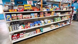 Un pasillo de un supermercado con estantes llenos de diversos productos alimenticios, como cereales, aperitivos y conservas.