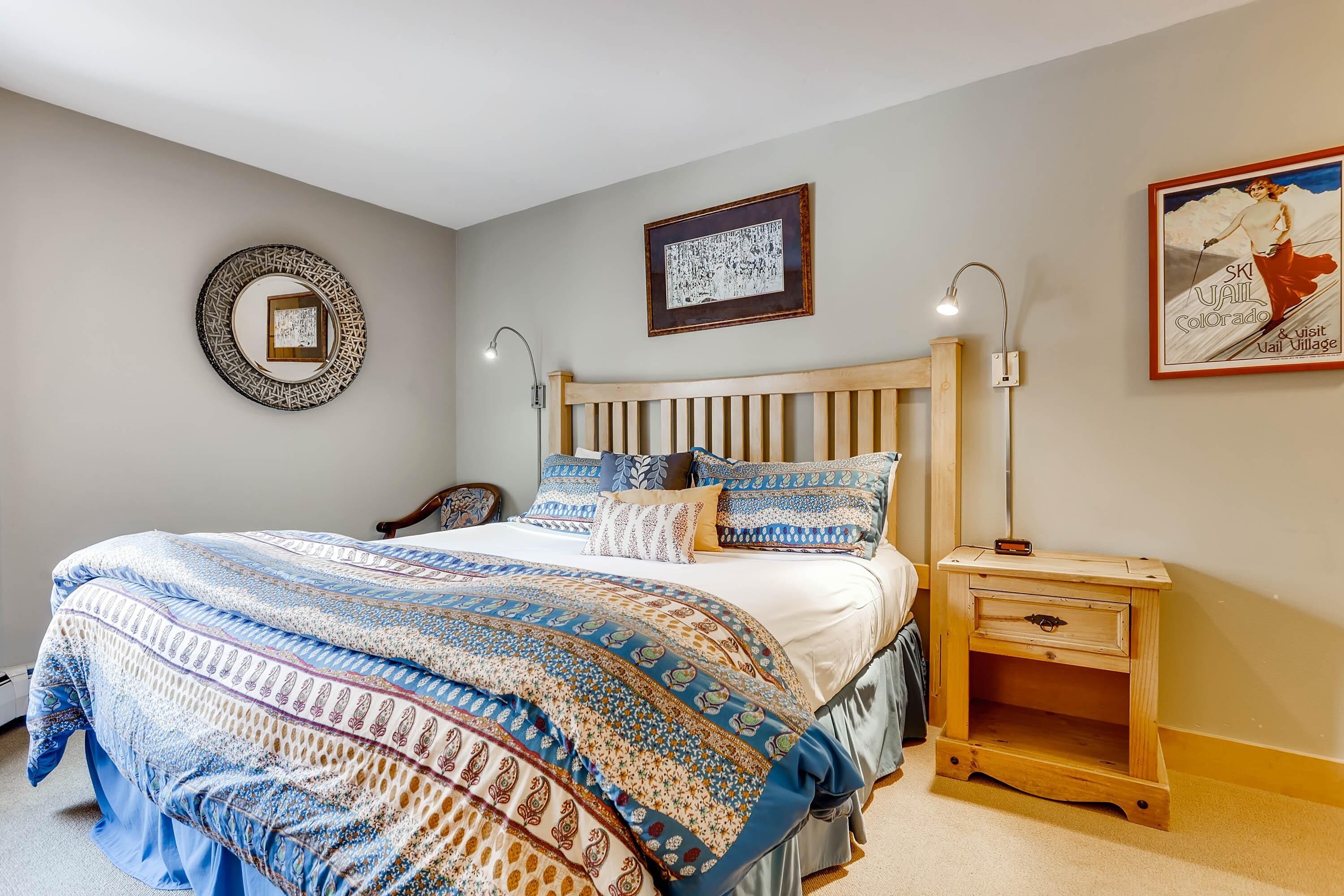 Una camera da letto con un letto grande, una testiera in legno, due lampade da comodino, un comodino e un quadro incorniciato al muro.