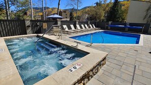 Relax by the rectangular pool, surrounded by a deck and adjacent hot tub with a water jet feature.