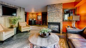 Un salon moderne avec une cheminée, des canapés en cuir et un téléviseur fixé au mur.