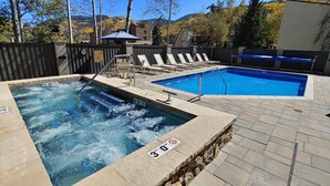 Un bain à remous et une piscine avec des chaises longues et une terrasse en bois.