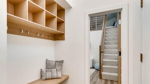 Un pasillo con un banco de madera, un estante empotrado y una escalera que lleva a otra habitación.