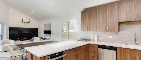 Una cocina moderna con armarios de madera, encimera blanca y electrodomésticos integrados.