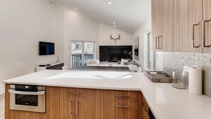 Una cocina moderna con una isla central, armarios de madera, horno empotrado y chimenea.