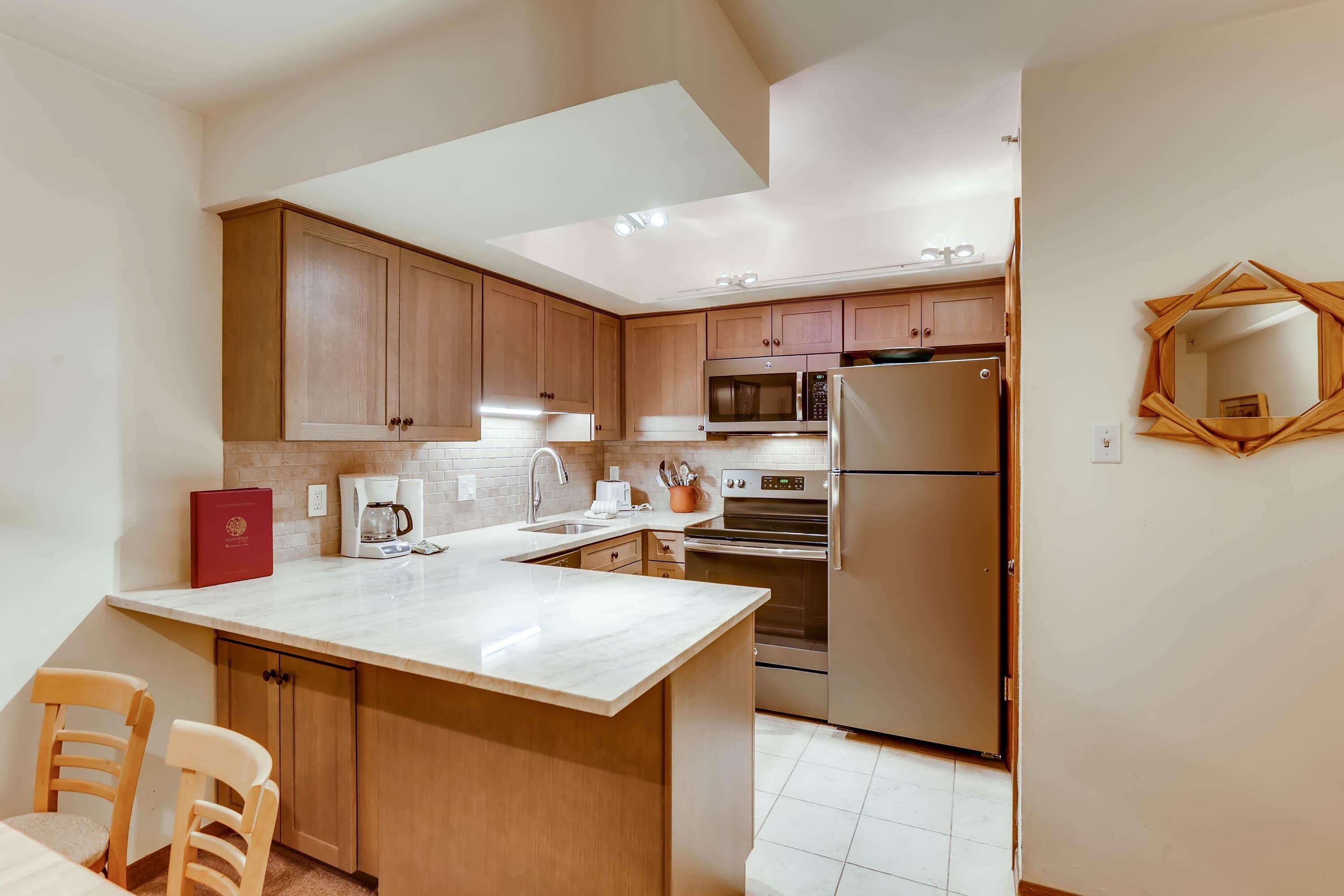A modern kitchen with wooden cabinets, a large island, stainless steel appliances, and a unique geometric mirror.