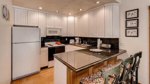 A modern kitchen with white cabinets, a central island, and a microwave. - Westwind 406 2BD 2BA Diamond Condo in Lionshead Village (Vail)