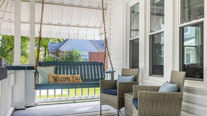 A porch with a swing, wicker chairs, and a 'Welcome Y'all' sign.