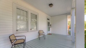 Un portico coperto con due sedie e una porta che dà su un percorso coperto.
