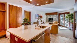 A modern kitchen with a central island, wooden cabinetry, and a stone backsplash. - Westwind 101 2bd, 2BA Diamond Condo in Lionshead Village (Vail)