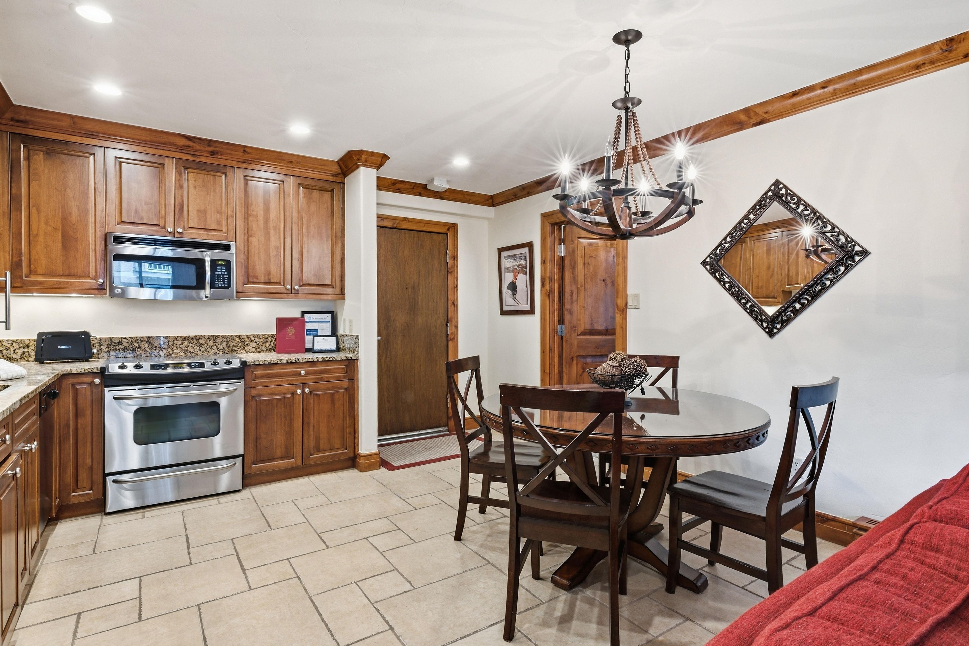 A kitchen with wooden cabinets, a microwave, an oven, and a chandelier.