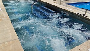 Una piscina con fuente, sillas de descanso y vistas a las montañas.