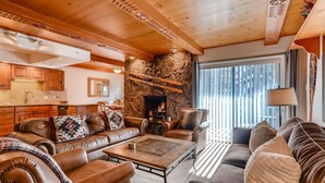Una sala de estar acogedora con sofás de cuero, una chimenea y una pared de piedra.