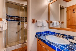 Une salle de bain avec une douche à parois de verre, un lavabo orné de carreaux bleus et un meuble en bois.