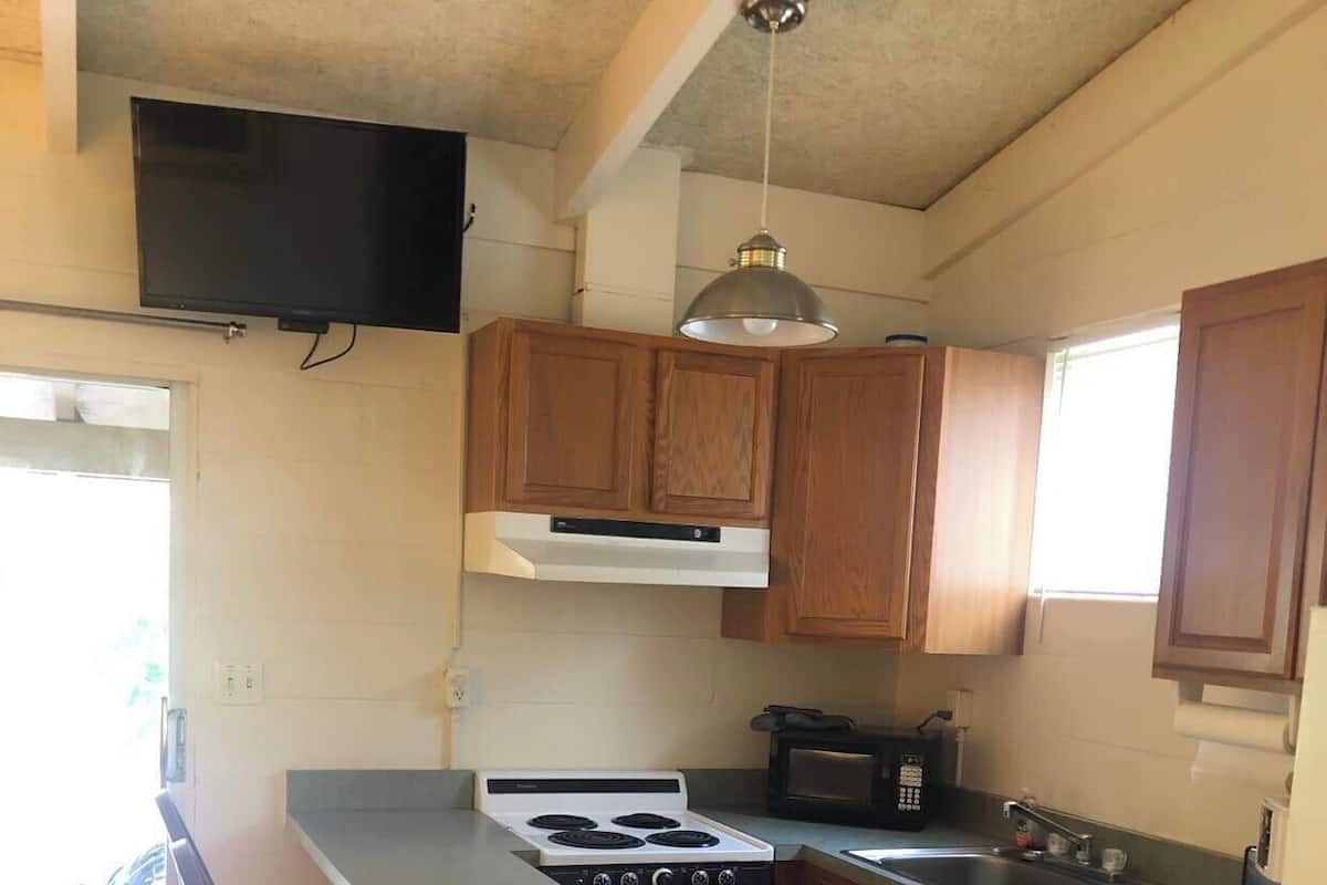 A kitchen with wooden cabinets, a built-in stove, a microwave, and a bar stool.
