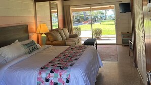 Une chambre d’hôtel avec un grand lit, un canapé, une télévision et une vue sur un terrain de golf.