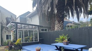 A backyard with a blue patio, potted plants, and a wooden fence. - B-Love's Guest House (Oakland)