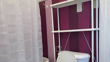 A bathroom with a white toilet, a white bathtub, and a purple wall.