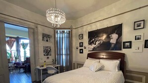 A bedroom with a large bed, a chandelier, and a wall with framed pictures. - B-Love's Guest House (Oakland)