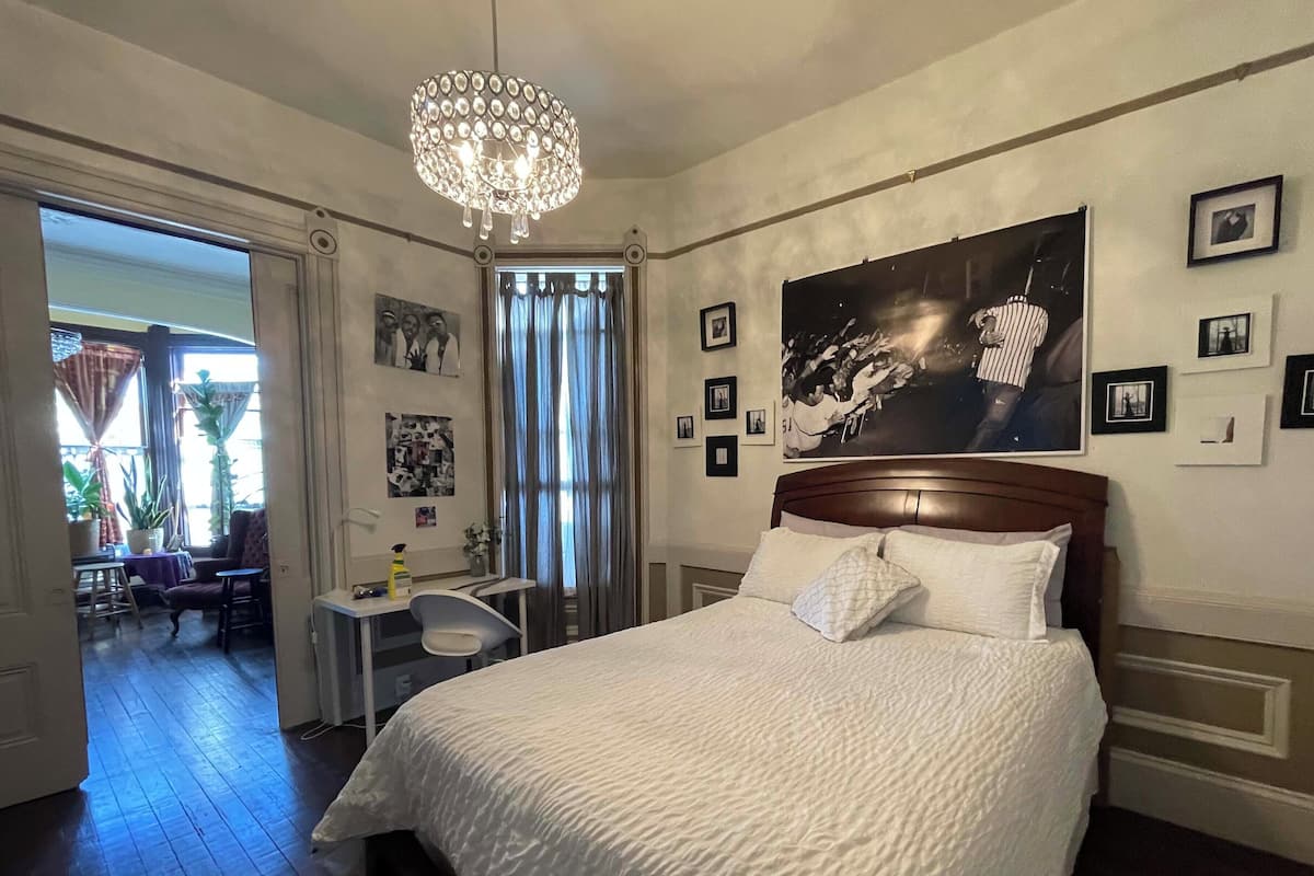 Une chambre à coucher avec un grand lit, un lustre et un mur orné de tableaux encadrés.
