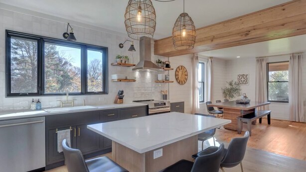 A modern kitchen with a large island, dark cabinetry, and pendant lighting.