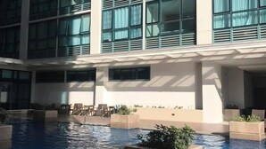 Um hotel moderno com uma grande piscina interior, várias varandas e áreas de estar ao ar livre.