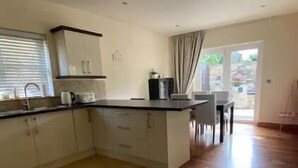 A modern kitchen with white cabinets, a black countertop, and a dining area with a table and chairs.
