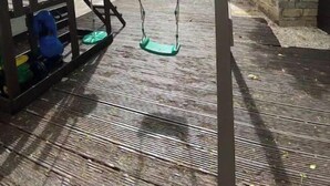 A wooden deck with a swing set and a play structure.