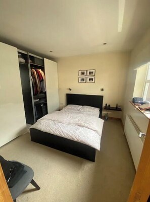 Une chambre à coucher avec un lit, une armoire, un bureau et une fenêtre.