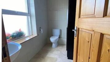 Un baño con inodoro, ventana y lavabo.