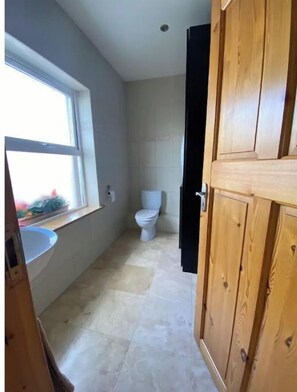 Une salle de bain avec des toilettes, une fenêtre et un lavabo.