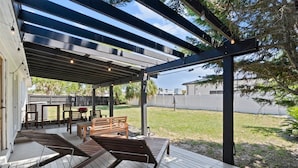 A covered patio with wooden furniture, including a bench and a table. - Casa Coco: Updated Home Walking Distance to Beach (Jacksonville Beach)