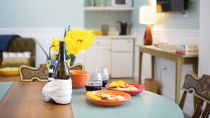 A dining table with plates of food, a bottle of water, and a vase with yellow flowers. - Willow Suite ~ 1 of 5 Unique Stays at Basswood ~ Ground Floor with Ramp Access (Capon Bridge)