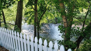 A white picket fence with a river and trees in the background. - Willow Suite ~ 1 of 5 Unique Stays at Basswood ~ Ground Floor with Ramp Access (Capon Bridge)