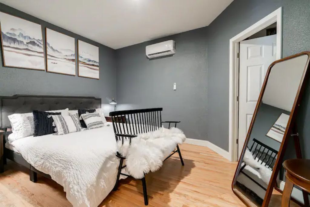 Une chambre à coucher avec un lit, une chaise, un miroir et des œuvres d’art accrochées au mur.