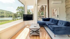 Ein modernes Wohnzimmer mit einem großen Fenster, einem Flachbildfernseher, einem blauen Sofa und einem Holztisch.